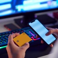 Person holding phone in one hand and credit card in another hand.